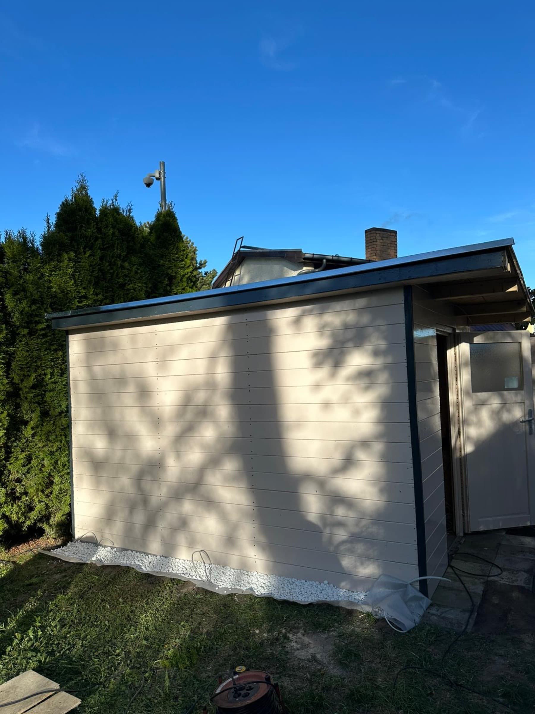 Fertig gestelltes Gartenhaus mit weißer Holzschalung